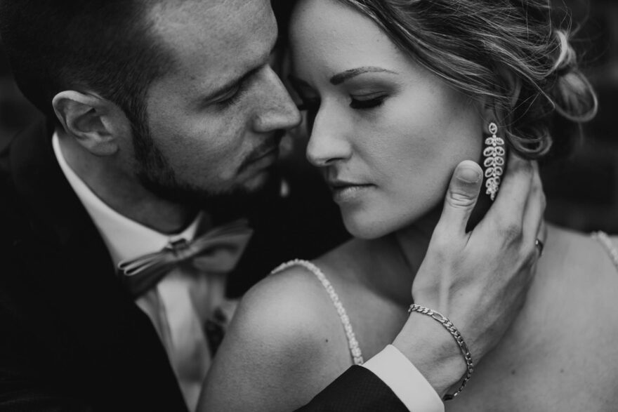 Braut und Bräutigam küssen sich unter dem Regenschirm, es ist dunkel und es regnet.