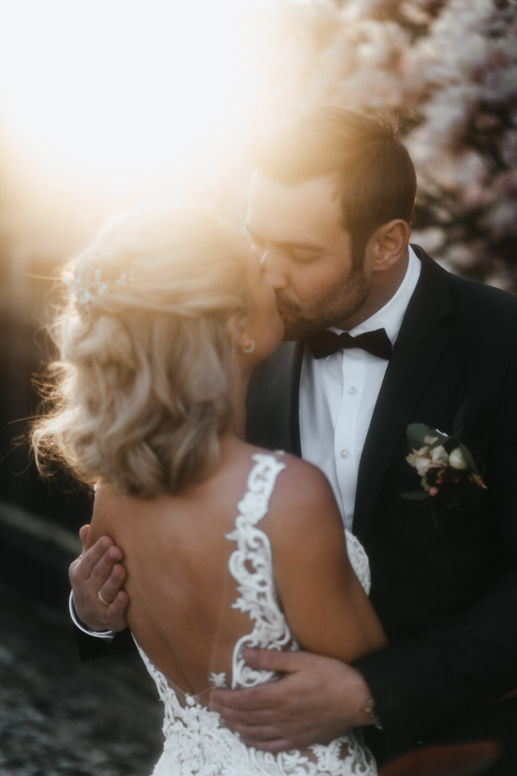 Hochzeitsfotografin NRW - das brautpaar steht vor der blühender Magnolie im Sonnenuntergangslicht und küsst sich
