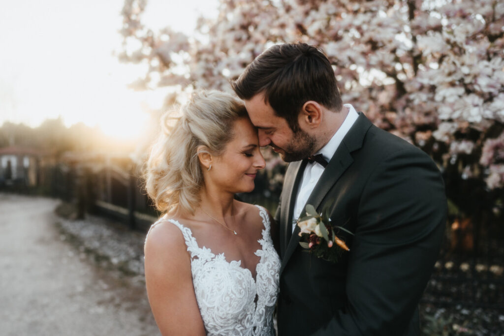 Ein Portrait vom Brautpaar vor einem blühenden Magnolienbaum